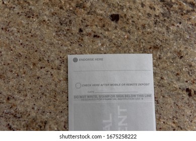 Back Of Bank White Check Endorsement Over Granite Background