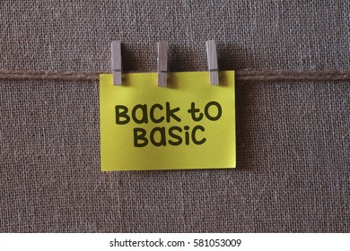 back to basic text on a yellow sticky note with three clips