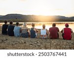 Back, beach and people on ground, relax and calm for meditation retreat, peace and nature. Group, outdoor and seaside with weekend break, summer holiday and rest with water, friends and getaway trip