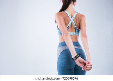 Back of beautiful fitness woman. Fitness girl do sport exercises isolated over gray background