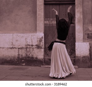 the back of a belly dancer as she dances in the street
