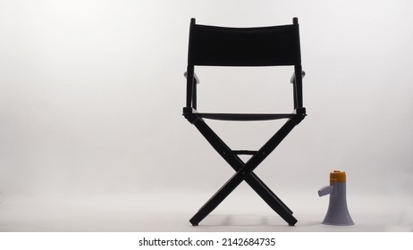 Back Of Black Director Chair And Megaphone On White Background.