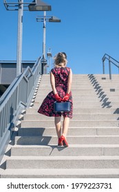 Back Of Blonde Woman In A Red Dress Walking Up Stairs Outside