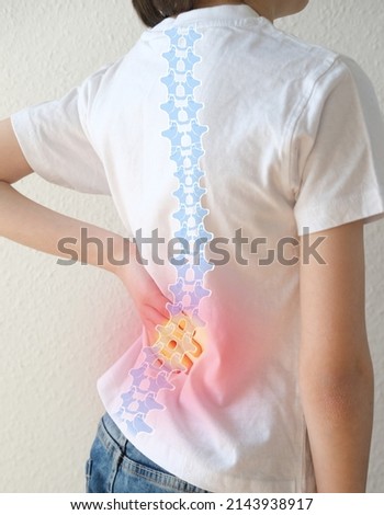 back of boy, child 8-10 years old in a white t-shirt grabbed a sore spot, curved spine, red spot as symbol of pain in spine, concept of osteochondrosis, scoliosis, back pain, intervertebral hernia