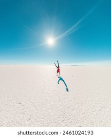 Back of a boy doing cart wheels at Uyuni salt flats in Bolivia. Sunflare