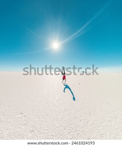 Back of a boy doing cart wheels at Uyuni salt flats in Bolivia. Sunflare