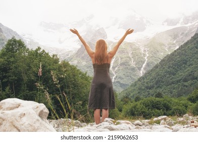 Back Of Caucasian Reddish Haired Woman Raising Hands Up In Mountains In Summer Time Feeling Happiness And Freedom. Bucket List