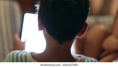 Back of child head staring at screen device at night - Powered by Shutterstock