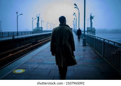 Back of cinematic young man in winter coat walking outside in urban city on bridge on a moody, foggy, winters night. - Powered by Shutterstock