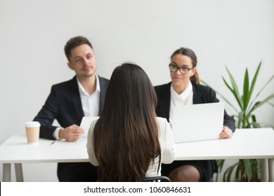 Back Close Up View Of Female Applicant Being Interviewed By Two HR Managers Reading Her Resume, Checking Data On Laptop, Asking Questions For Job Position. Employment, Hiring, First Impression Concept