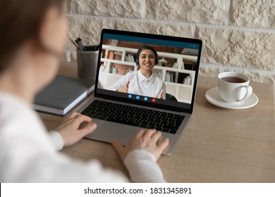 Back Close Up View Of Female Look At Laptop Screen Talk Speak With Indian Coach Or Trainer, Study Online At Home. Woman Have Webcam Digital Virtual Conference Or Online Web Lesson With Ethnic Teacher.