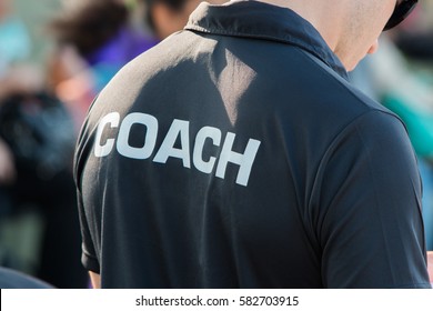 back of a coach's black shirt with the white word Coach written on it - Shutterstock ID 582703915