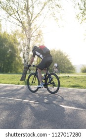 Back of a cyclist with a backpack while riding in the city on a bike. Man in sportswear and a helmet rides the city park.
