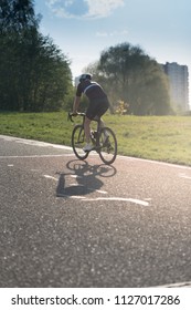 Back of a cyclist with a backpack while riding in the city on a bike. Man in sportswear and a helmet rides the city park.