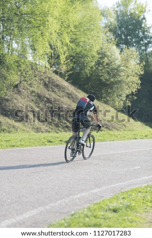 Back of a cyclist with a backpack while riding in the city on a bike. Man in sportswear and a helmet rides the city park.