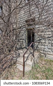 Back Door To A 19th Century School Overgrown With Tree Branches