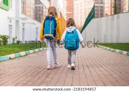 Back to elementary,primary school.Little girls,sisters with big backpack go in hurry,late to first grade alone in autumn morning.Education,future of children.Happy,unhappy pupils kids walk themselves.