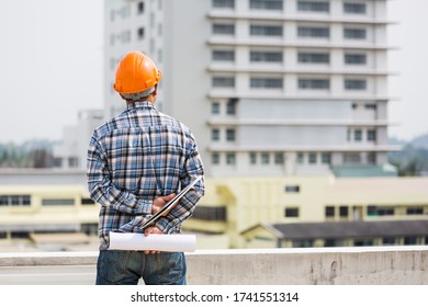 back of engineering man with computer notebook in hand and green building background - Shutterstock ID 1741551314