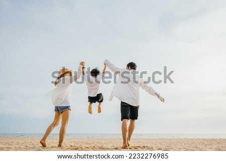 Back family mother, father and son holding hands and jumping in air at dawn time, Family outdoor activities, Happy Asian family people have fun healthy lifestyle together on beach, holiday vacation