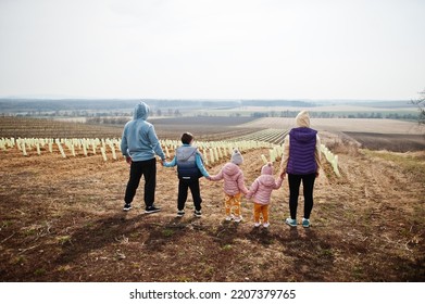 Back Of Family Stand Against Vineyard In Early Spring.