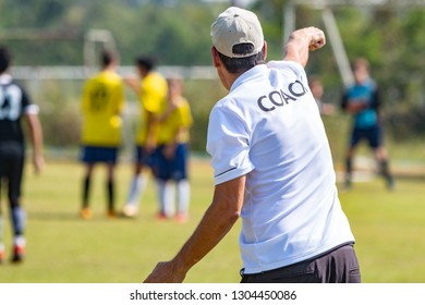 Back Of Football Coach Wearing White COACH Shirt At An Outdoor Sport Field Coaching His Team During A Game, Good For Sport Or Coaching Concept