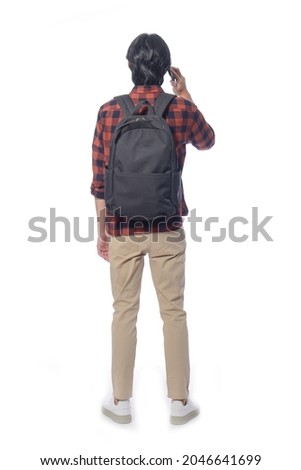 Back Full body portrait of young man with jeans using cellphone with backpack  in studio isolated on white background

