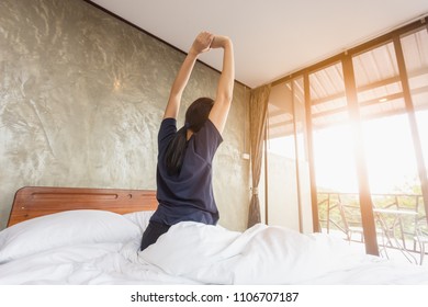 The back of the girl woke up in the morning on the bedroom with fresh duvets. - Shutterstock ID 1106707187
