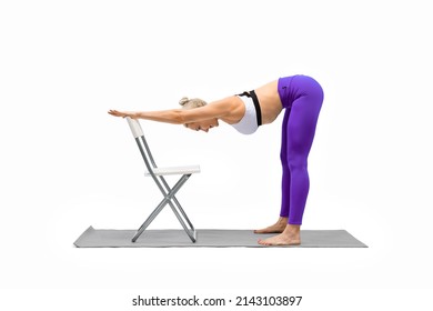 Back and hamstrings stretching, Iyengar yoga with props. Caucasian woman does deep bend holding on to the chair with her hands, isolated on white. Fitness advertising, sport, female health, workout - Powered by Shutterstock