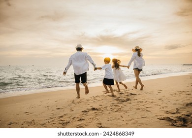 Back of happy Asian parents with their daughters enjoying playful at beach. Little girls bond with their mother and father running jumping and pretending to fly with arms wide open. Family fun in sun. - Powered by Shutterstock