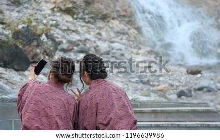 Back of Japanese women who selfie while relaxing with foot spa onsen at natural hot spring town kusatsu gunma Japan