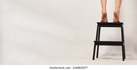 Back Legs And Barefoot Stand On Tiptoe On A Step Stool Or Wooden Stairs With White Background.