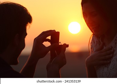 Back light of a couple proposal of marriage on the beach at sunset - Powered by Shutterstock