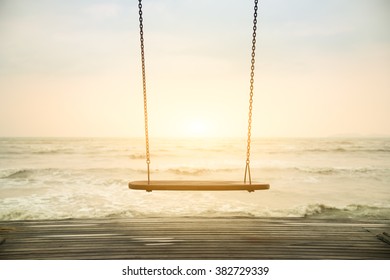 Back light of silhouette empty swing on the beach sunset  