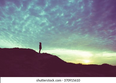 Back light silhouette of a man standing on a hill, overlooking, filtered vintage - future, power, achievement concept