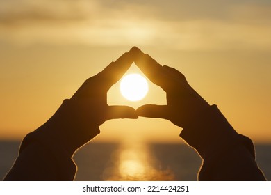 Back Lit Photography. Human Hands Show Frame Of House In Front Of The Sun Disk On The Golden Sky. Let's Light A Fire At Home. Light Of Happiness. Beauty Of Family Life. Conceptual Image