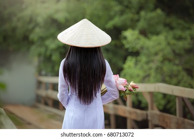 The back of a long haired woman wearing a hat Dressed Ao Dai  traditional Vietnamese dress. - Powered by Shutterstock