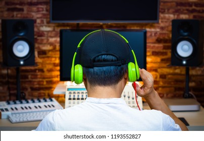Back Of Male Asian Music Producer Listening Song In Home Recording Studio