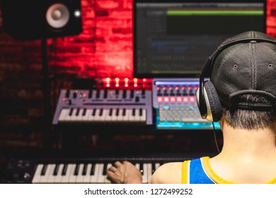 Back Of Male Asian Music Producer Arranging A Song In Home Recording Studio