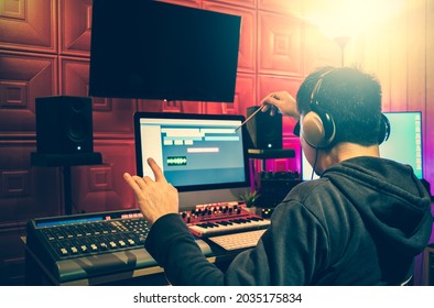 Back Of Male Asian Producer Pretended Like A Symphony Music Conductor While Enjoy Listening, Editing And Mixing A Song In Home Recording Studio