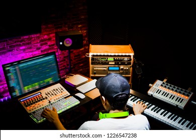 Back Of Male Asian Producer Working In Sound Design Studio. Music, Film Score, Advertising Footage Digital Editing, Jingle Song, Voice Actor Recording, Post Production