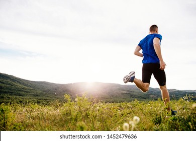back man runner running on summer plateau motley grass in sunset