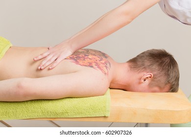 Back Massage. Massage Therapist Massaging Lower Back Region Of A Tattooed Man