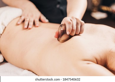 Back massage with vacuum cups - a professional masseur treats a patient