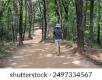 The Back of a Middle-Aged Woman Walking with Red Clay for Health