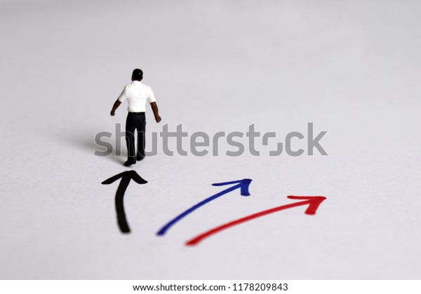 The back of a miniature man standing in front
of three color direction.