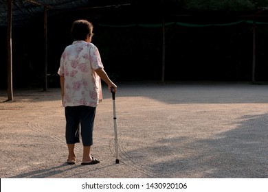 Back Of Old Woman Standing With Walking Stick. Aging Society Concept.