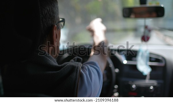 Back\
of older man driving on road. Senior driver on\
trip