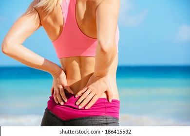 Rückenschmerzen. Sportliche Fitness-Frau, die die Muskeln ihres unteren Rückens rieb. Sportliche Sportverletzung.