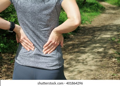 Back Pain. Athletic Fitness Woman Rubbing The Muscles Of Her Lower Back. Sports Exercising Injury.