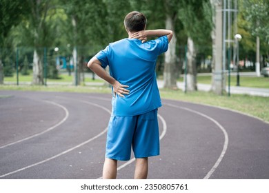 Back pain, athletic man with backache on a running track after workout, healthy lifestyle concept - Powered by Shutterstock